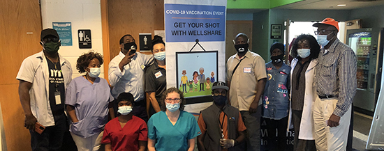Vaccination event staff posing for picture with banner.