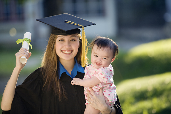 Graduating mom holding baby and diploma.